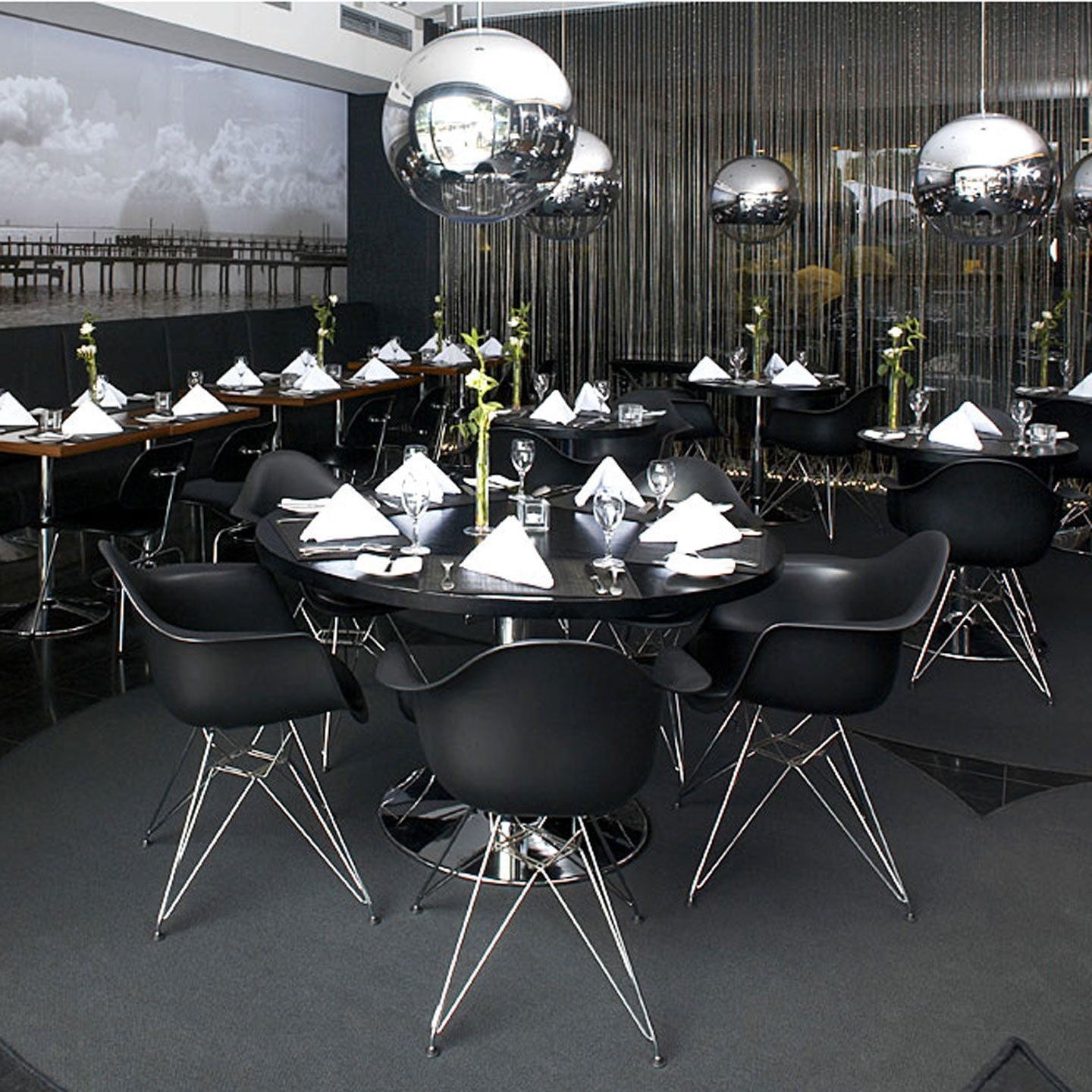 Modern restaurant interior with black chairs and round tables, featuring decorative elements.