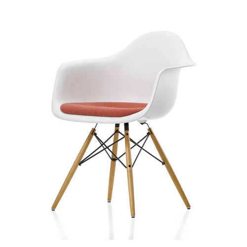 Modern Eames chair with white plastic seat and backrest, wooden legs, and red cushion on a white background