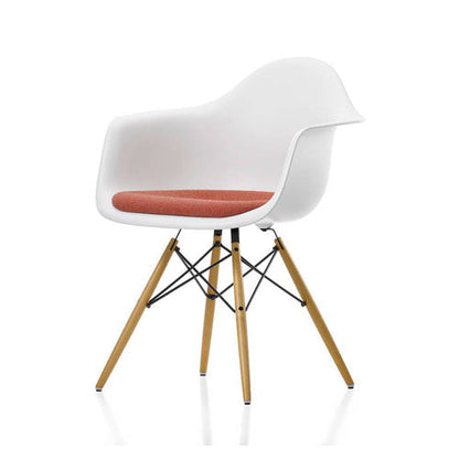 Modern Eames chair with white plastic seat and backrest, wooden legs, and red cushion on a white background